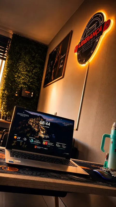 Escritório com o letreiro luminoso Liderança Radiadores na parede e o notebook na mesa
